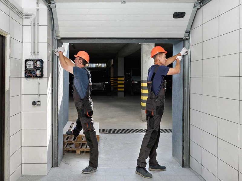 Professional technicians installing and aligning a residential garage door